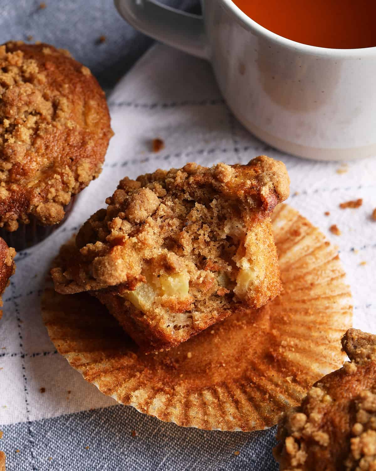 Apple cider muffin split open to show diced apple pieces and cinnamon crumb topping.