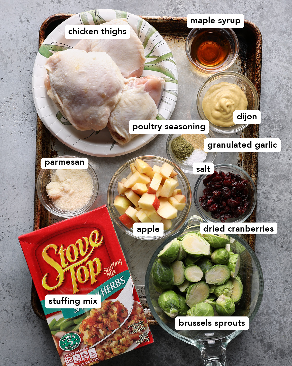 Chicken thighs, stuffing mix, Brussels sprouts, apple, dried cranberries, Parmesan, Dijon mustard, maple syrup, and seasonings for sheet pan chicken and stuffing.