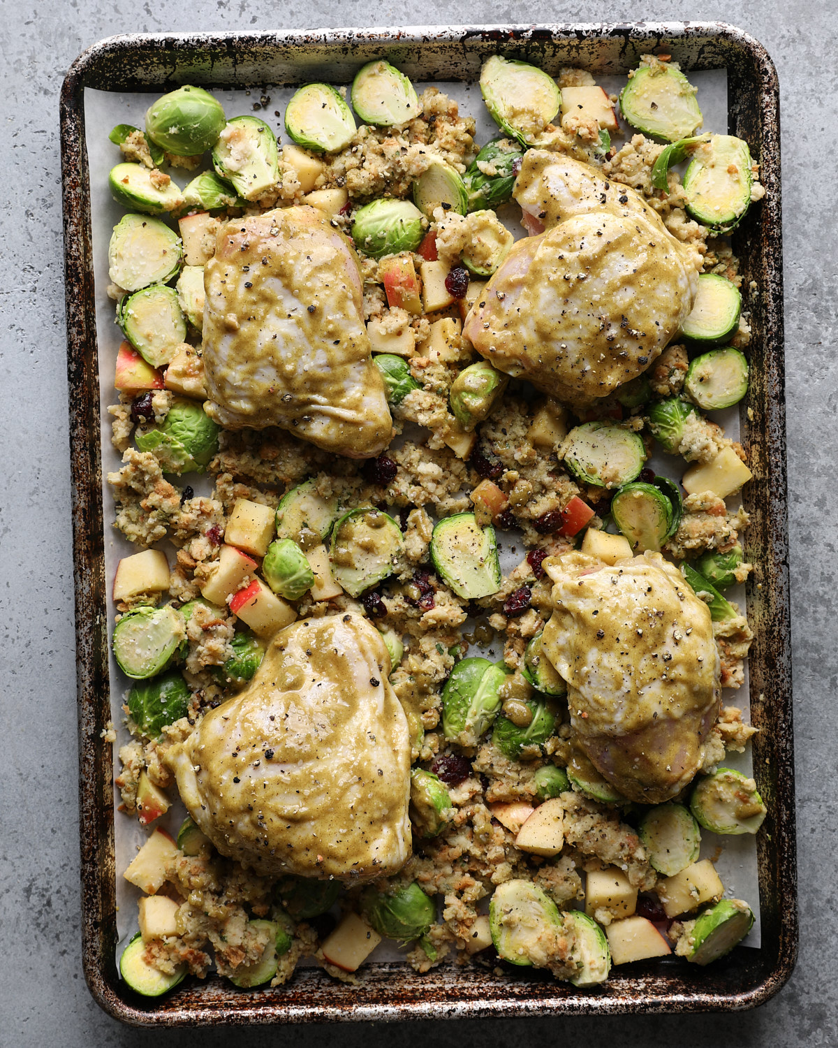 Four maple Dijon-coated chicken thighs arranged skin-side up on the stuffing and vegetable mixture before roasting.