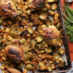 Maple Dijon chicken thighs surrounded by roasted stuffing, Brussels sprouts, apples, and cranberries.