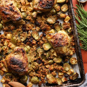 Maple Dijon chicken thighs surrounded by roasted stuffing, Brussels sprouts, apples, and cranberries.