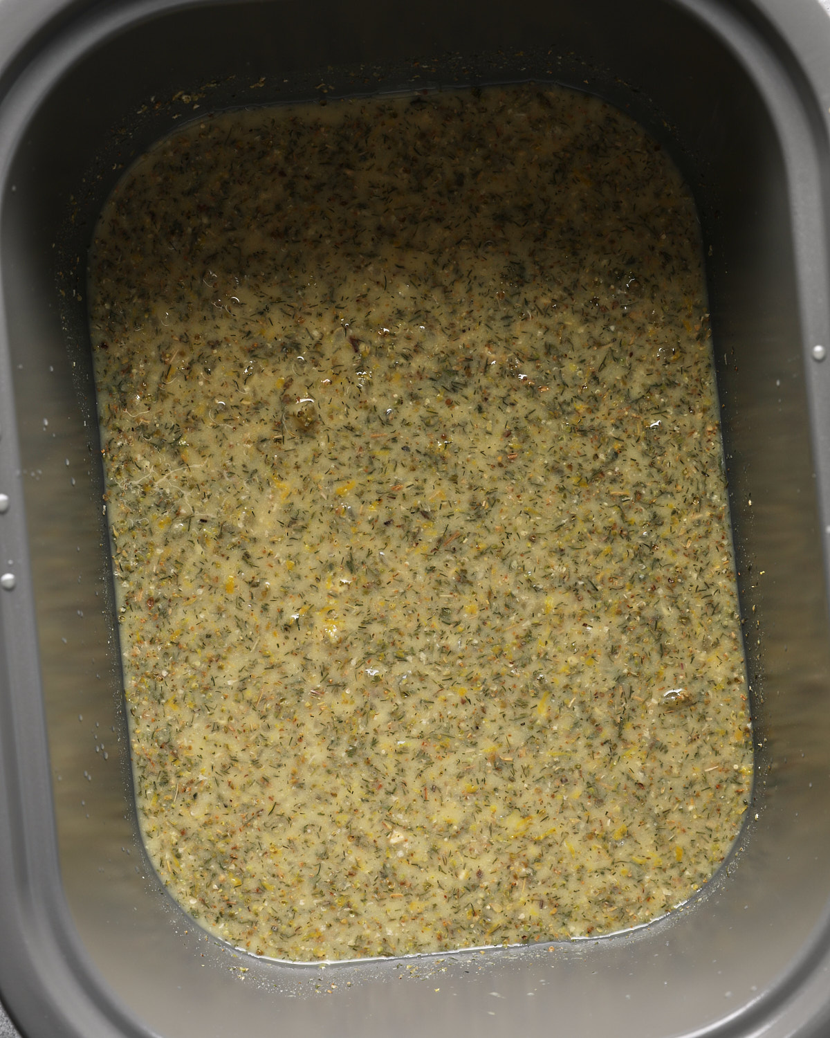 Lemon Dijon broth mixture with garlic and dried herbs in a slow cooker.