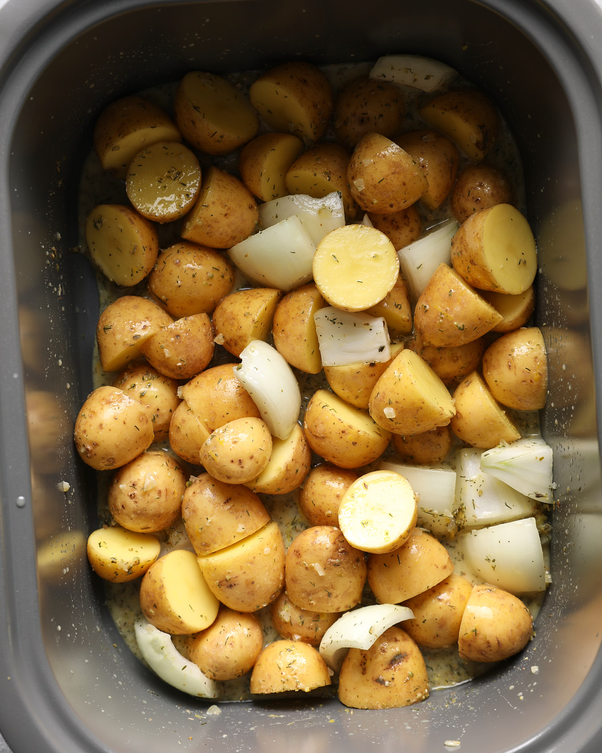 Yellow potatoes and onion wedges coated in lemon Dijon broth in a slow cooker.