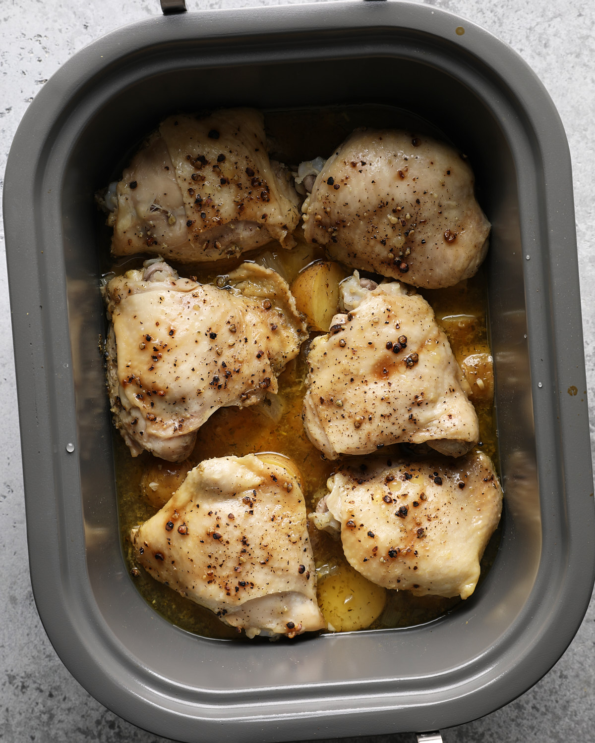 Cooked chicken thighs and fork-tender potatoes in a slow cooker.