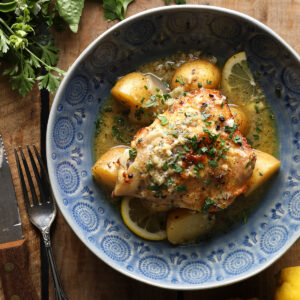 Slow cooker Greek lemon chicken and potatoes served in a blue bowl.