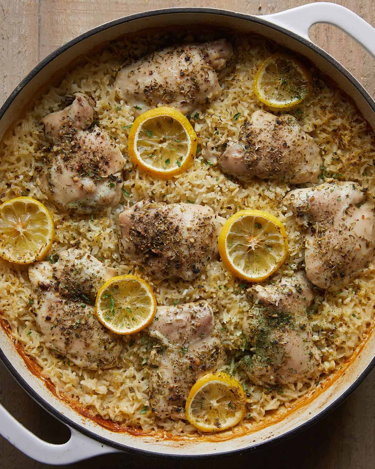 Baked lemon chicken and rice with cooked chicken thighs, tender rice, lemon slices, and herbs.